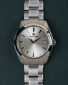 Grand Seiko Heritage Collection SBGV221 - Volledig horloge recht van boven met zilverkleurige wijzerplaat en stalen schakelband