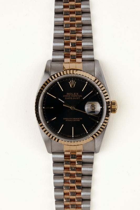 Rolex Datejust 16233 - vooraanzicht van de zwarte wijzerplaat, geribbelde gouden bezel en armband