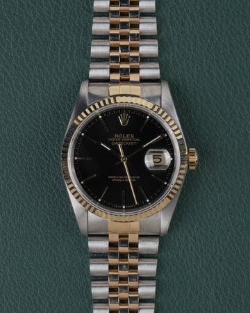 Rolex Datejust 16233 Black Dial 1991 - Volledig horloge recht van boven met zwarte wijzerplaat, gefacetteerde bicolor bezel en jubilee-band