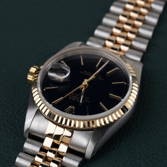 Rolex Datejust 16233 Black Dial 1991 - Ondersteboven aanzicht onder een hoek met de kroon links en de jubilee-band schuin naar boven rechts