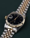Rolex Datejust 16233 Black Dial 1991 - Ondersteboven aanzicht onder een hoek met de kroon links en de jubilee-band schuin naar boven rechts